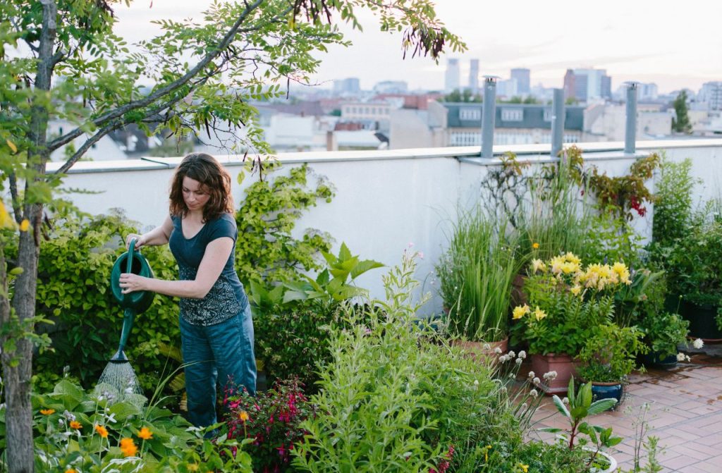 A woman waters her metopolitan garden made of potted plants.